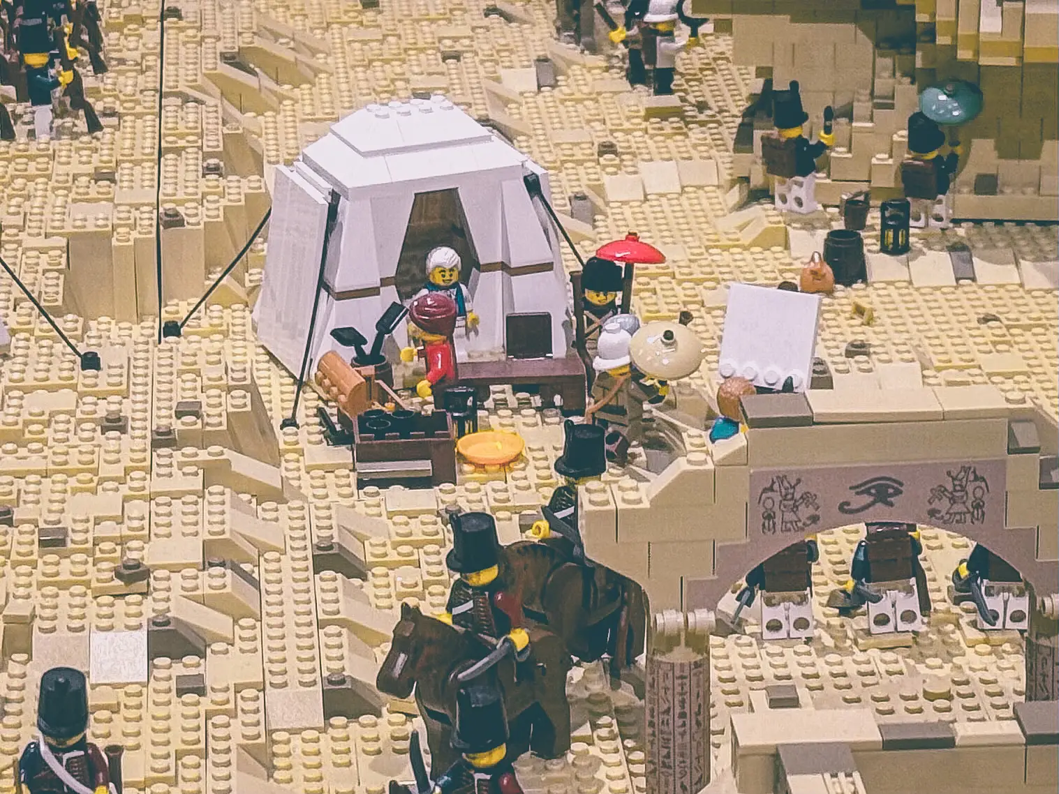 Close view of the LEGO Egyptian campaign build showing an open command tent furnished with table and chairs beside hieroglyph-carved stonework.