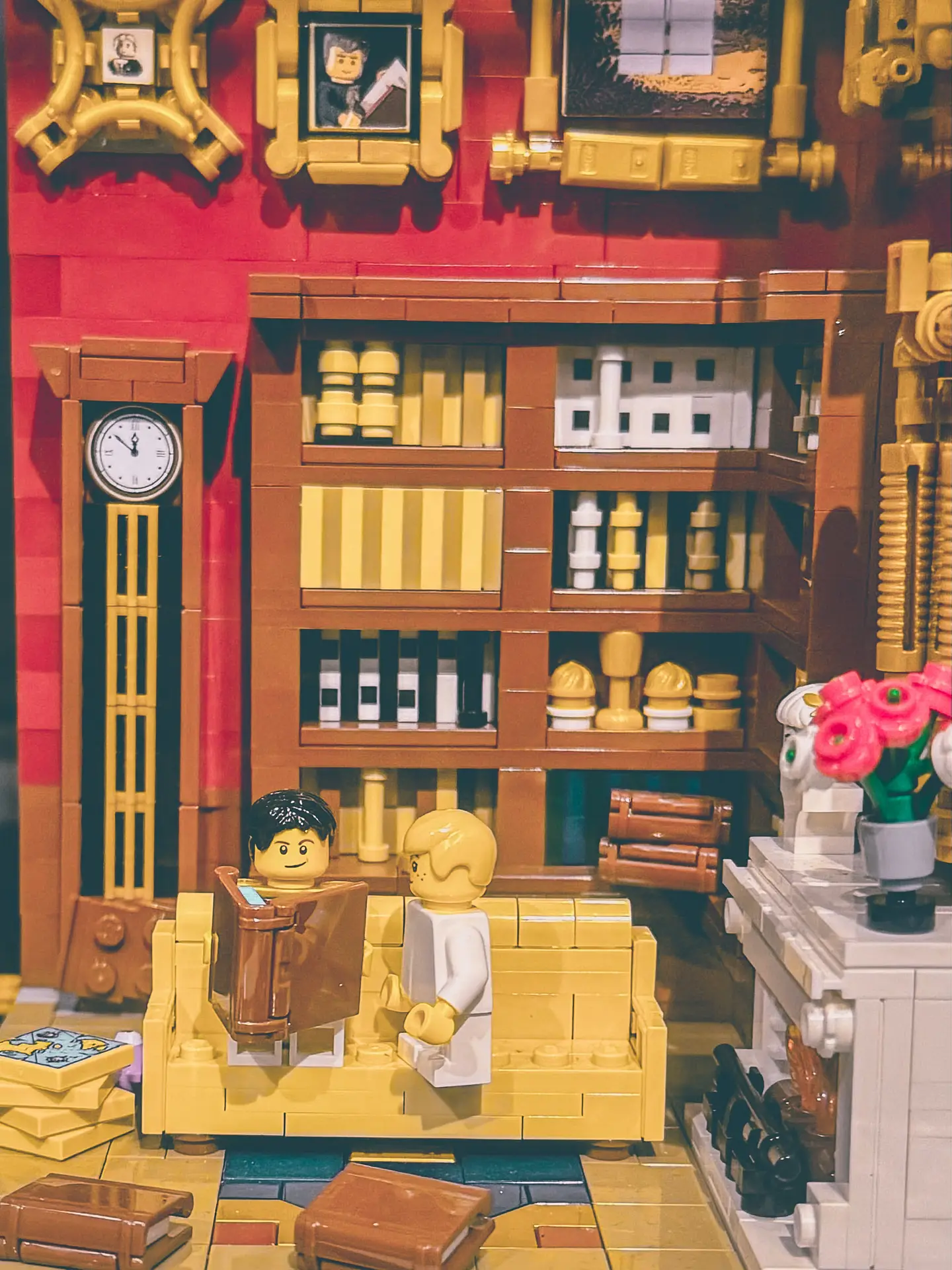 LEGO drawing-room build with Napoleon and the King of Rome on a sofa, a longcase clock and shelves of bottles and books behind them.