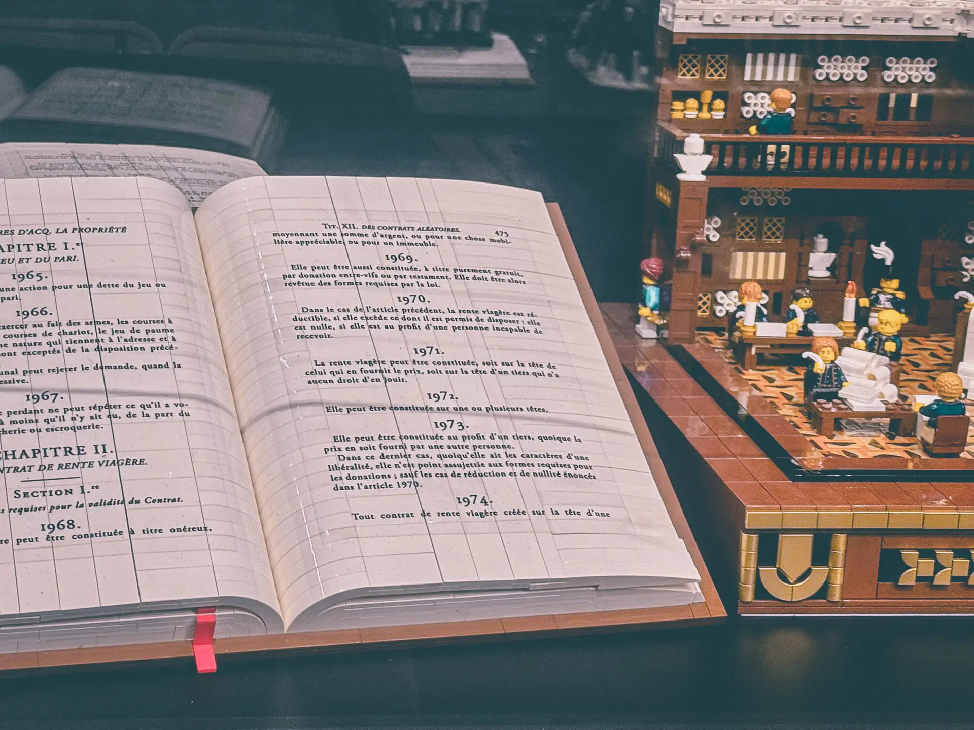 Close view of the LEGO Civil Code build, an open printed volume of the Code standing beside the assembled figures as a giant parchment.