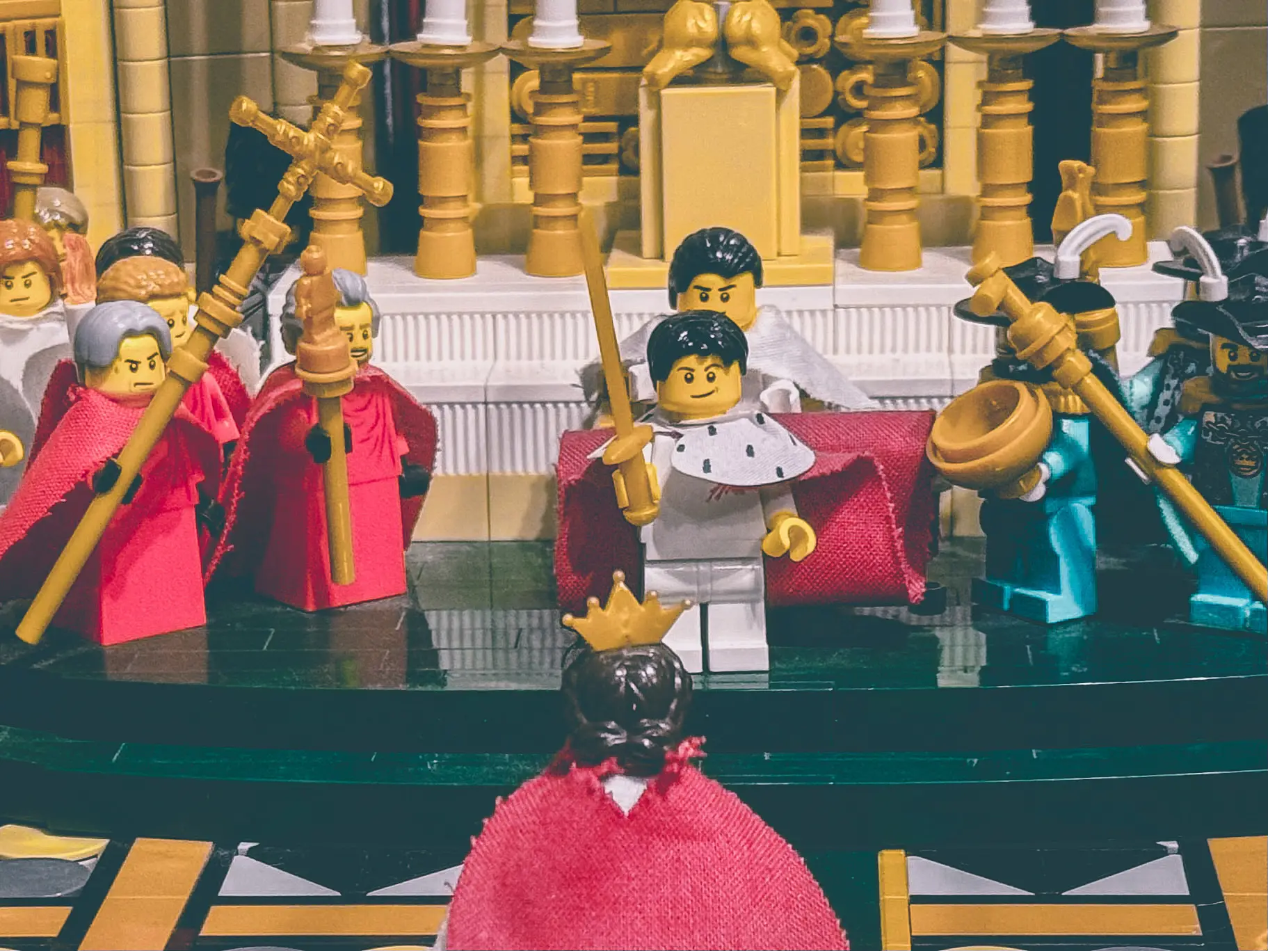 Close view of the LEGO coronation build showing a distinctly grumpy Pope Pius VII and equally unimpressed clergy in red robes behind the kneeling empress.