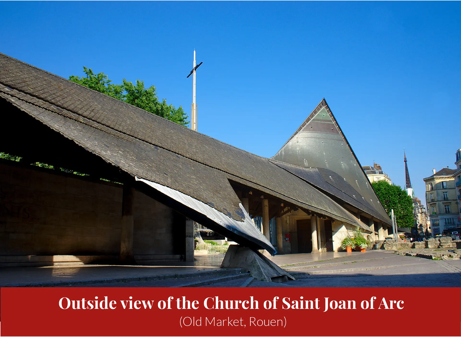 Exterior of the modern Church of Saint Joan of Arc in Rouen's Old Market, its sweeping roofline evoking an overturned longship, under a clear blue sky.