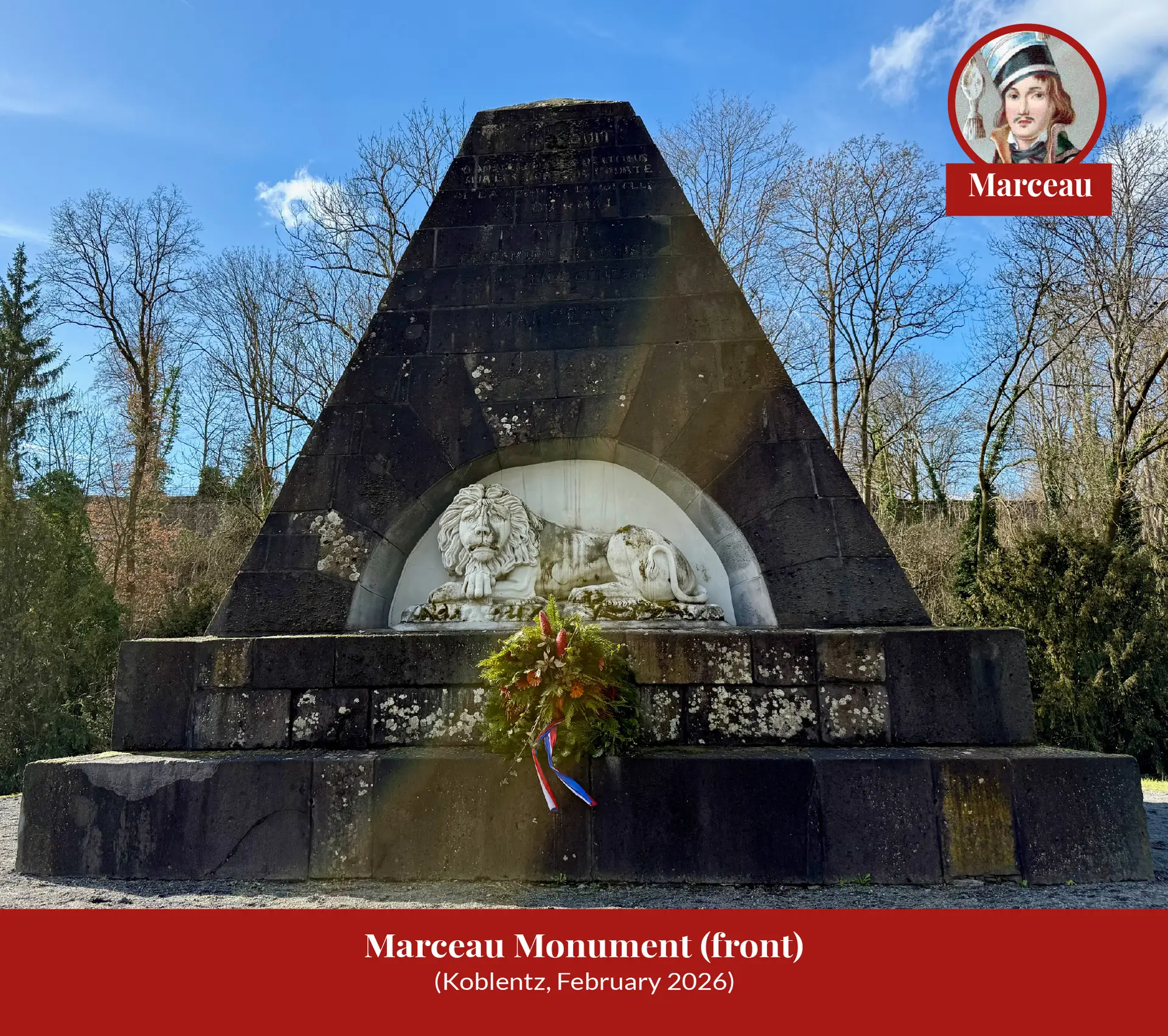 The pyramid-shaped Marceau monument at Koblenz seen head-on, a white stone lion couchant in its arched niche and a wreath with French tricolour ribbons at its foot.